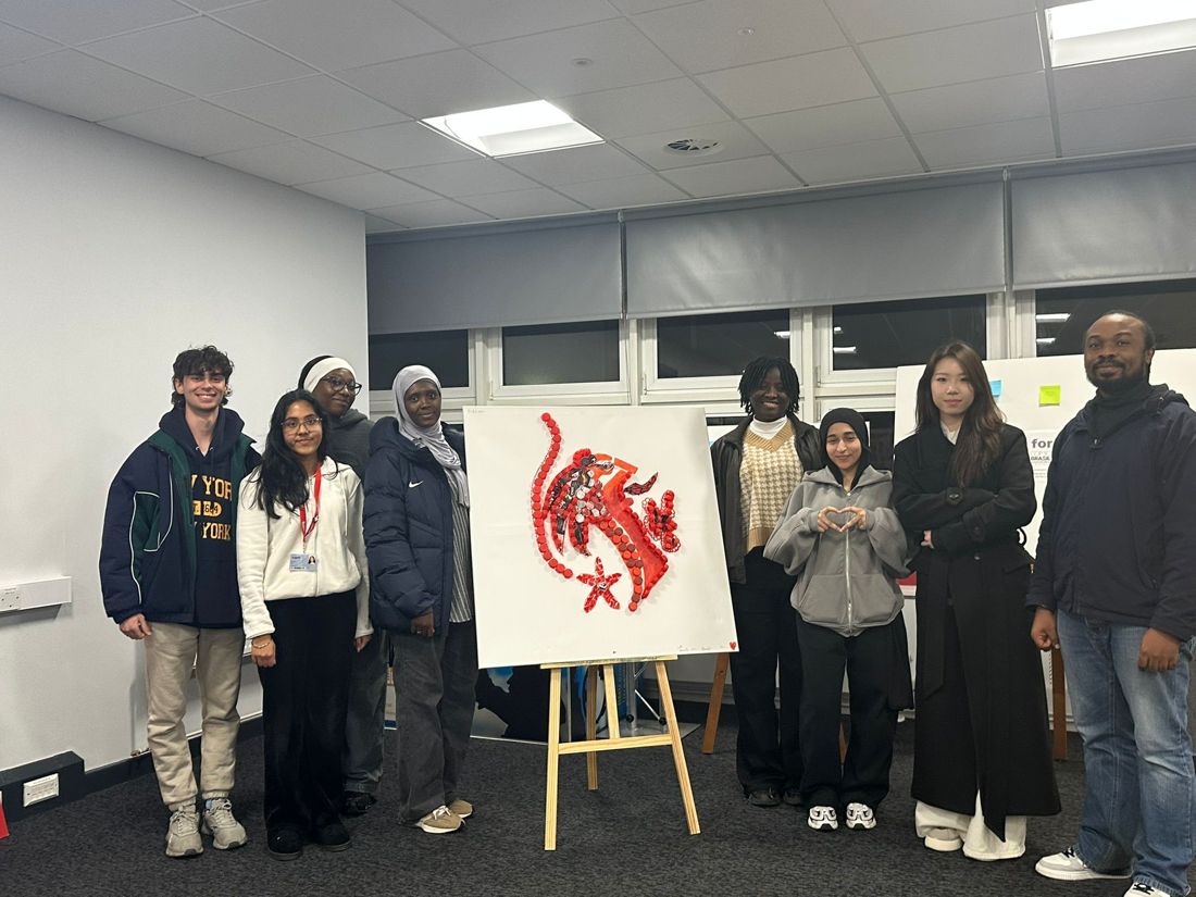 Workshop participants with their red bottle cap artwork on an easel