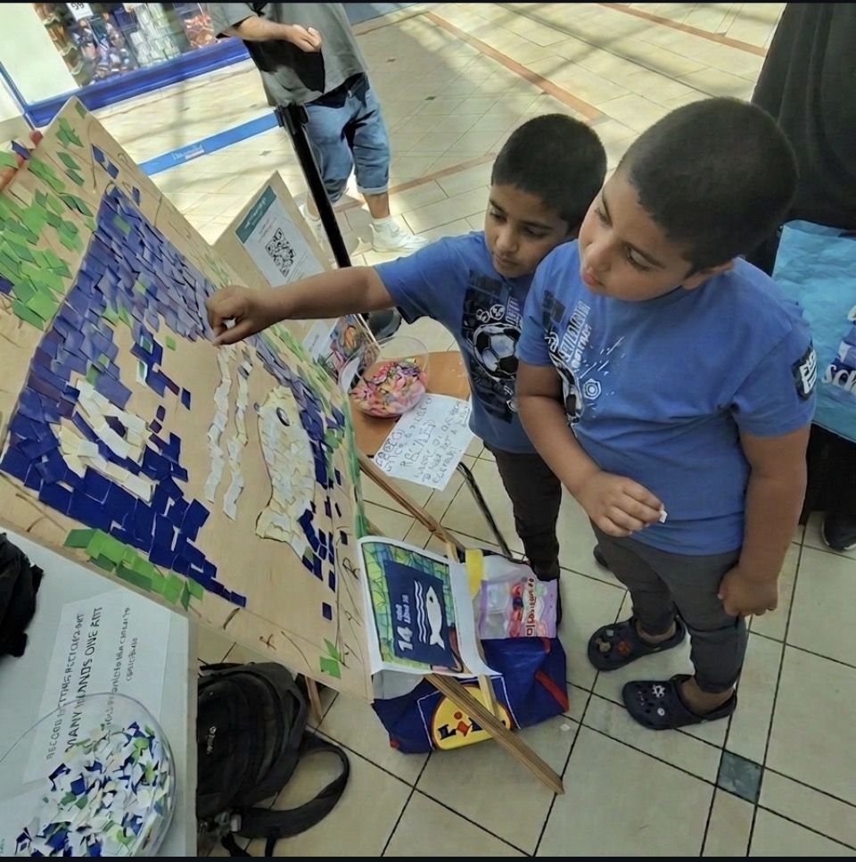 Two boys adding pieces to the SDG 14 Life Below Water mosaic panel