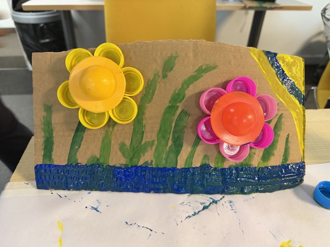 Cardboard artwork with flowers made from bottle caps